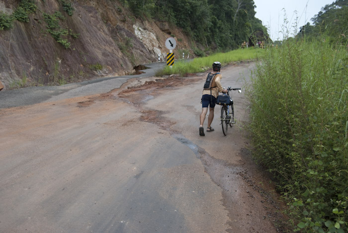 Micah walking bike up road past missing section